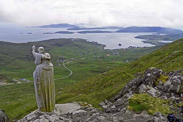 Estatua de mármol en la colina Heaval en la Isla de Barra en Escocia, con vistas a la bahía y al castillo de Kisimul