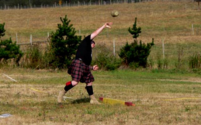 Hombre en kilt haciendo lanzamiento de peso en juego de las Highlands en Escocia