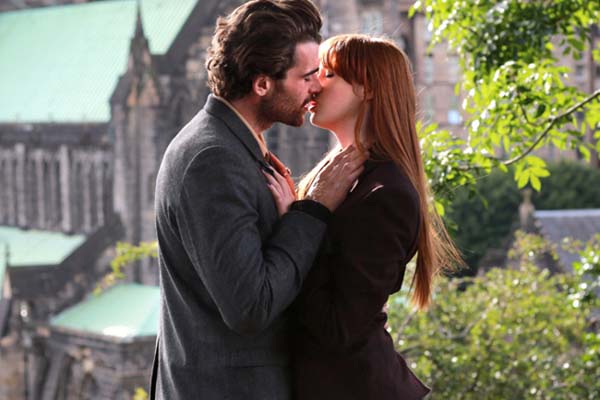 Protagonistas de "Buscando un final feliz" dándose un beso con la catedral de Glasgow de fondo
